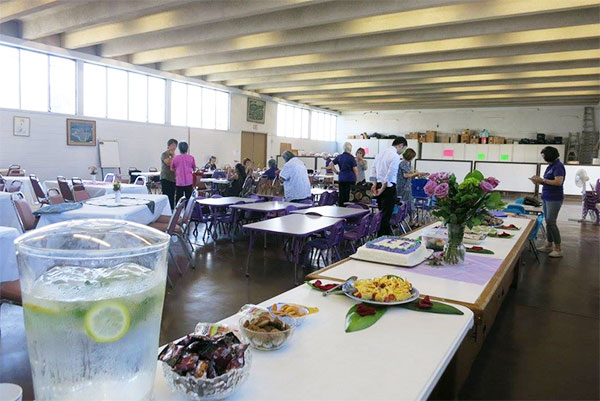 social hall with tables, one with cake, and people
